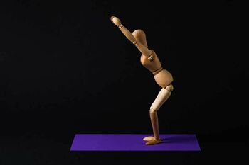 Symbolbild einer Holzfigur, die eine Übung auf einer Matte durchführt
